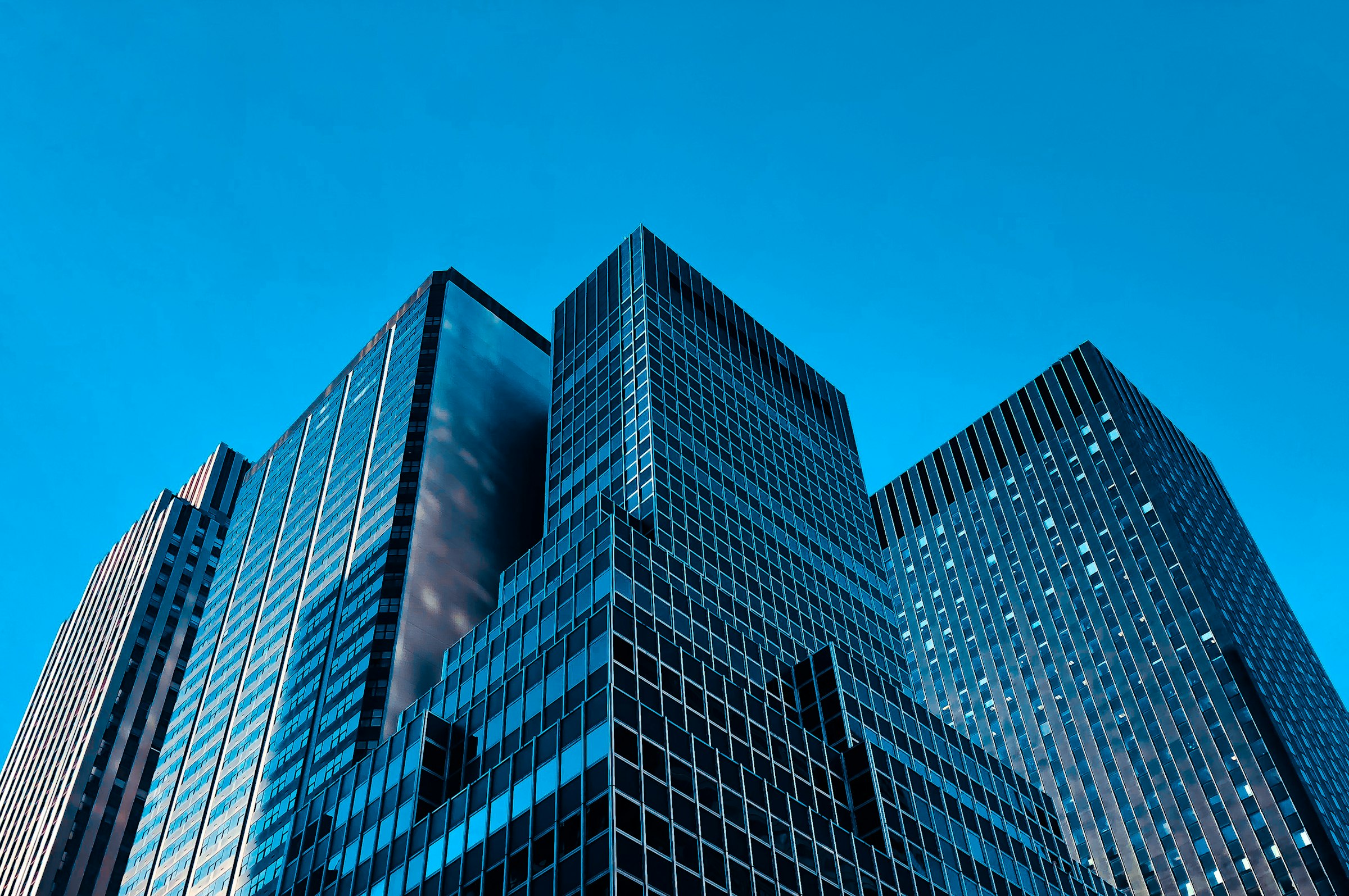 Glass office towers seen from street level against a clear blue sky